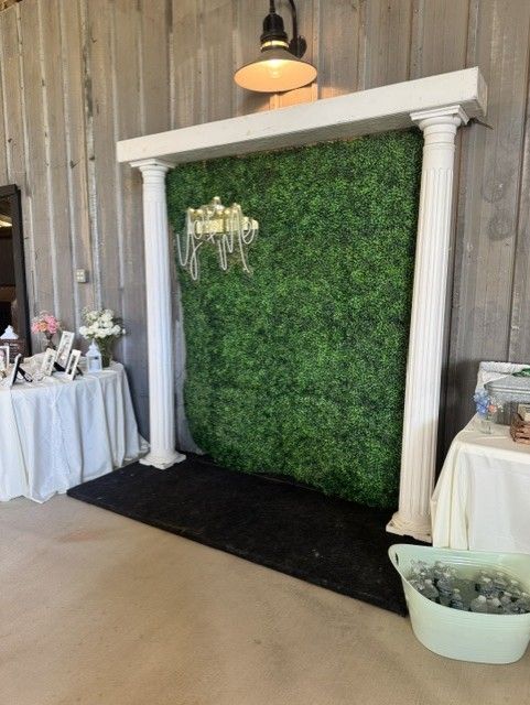 Greenery photo backdrop with white columns and a lit chandelier