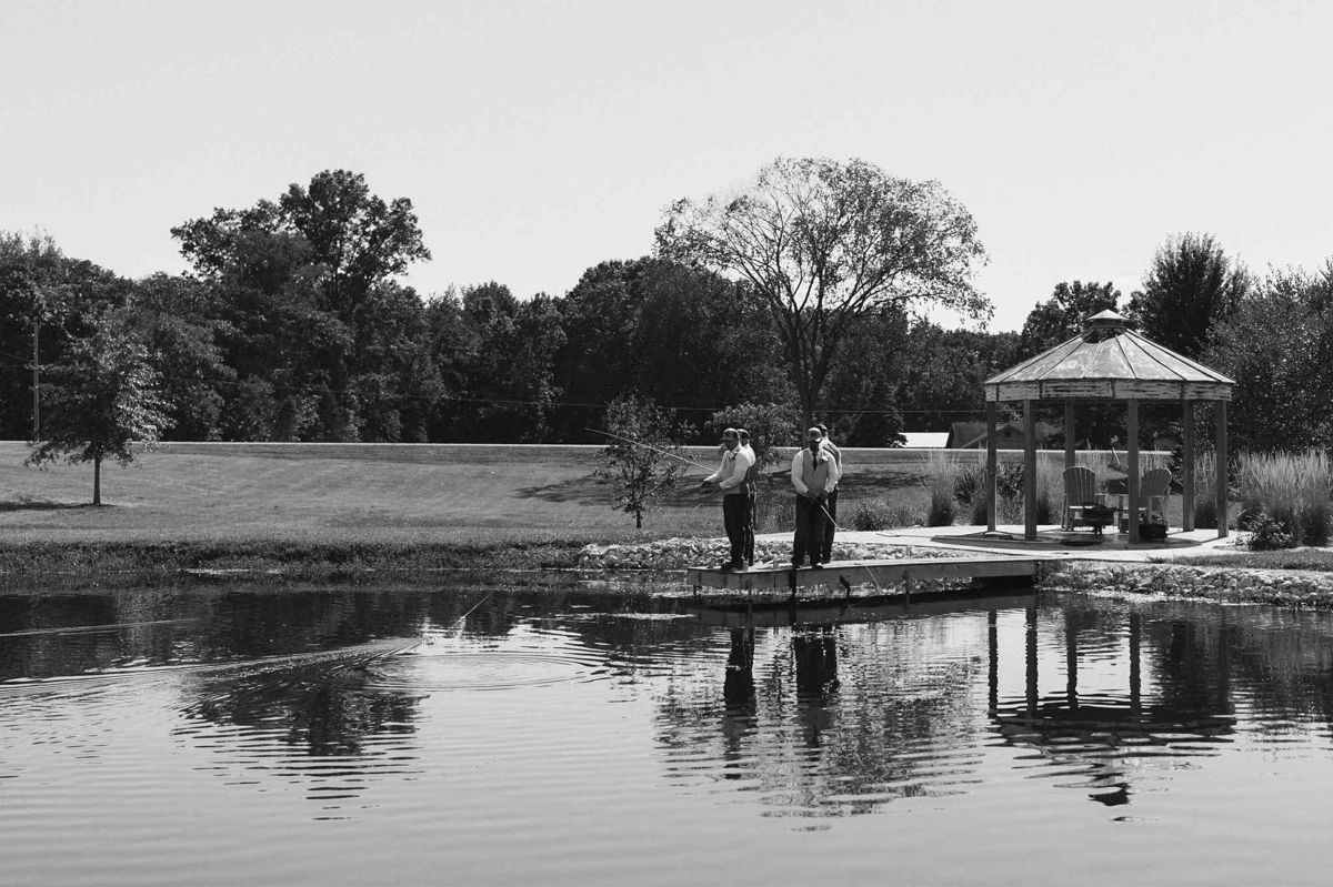Groomsmen fishing off the dock by the gazebo, black and white